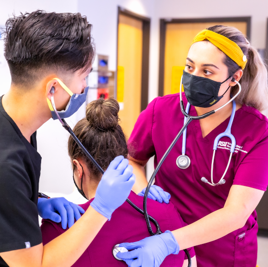 Man and Woman listening to 3rd woman's lungs with stethoscope